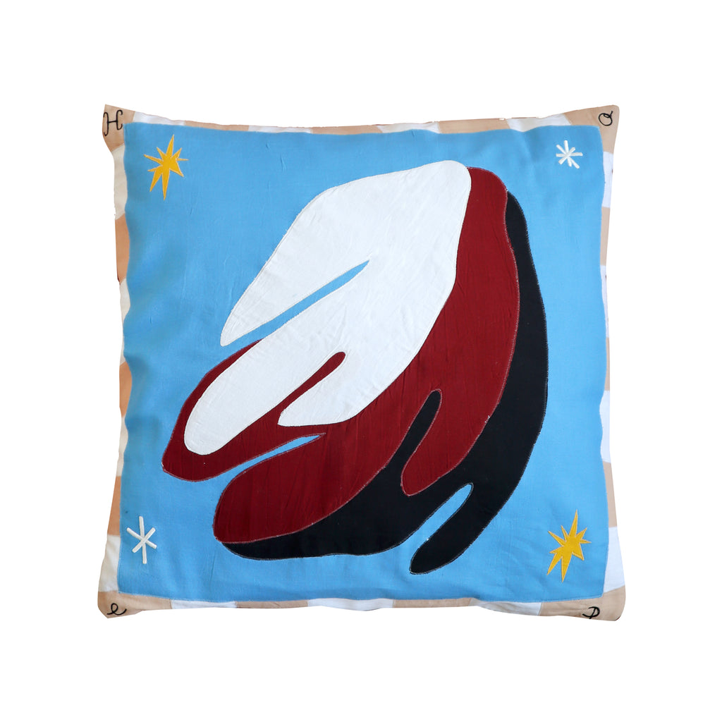 The cushion is blue and has a border of white and beige alternating rectangles. The design is white, red/brown and black and has yellow and white stars. 